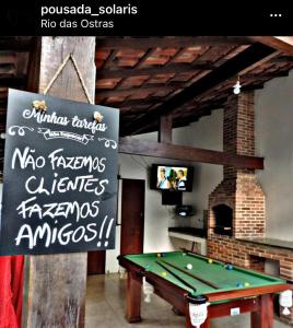a ping pong table in a room with a sign at Pousada Solari s in Rio das Ostras