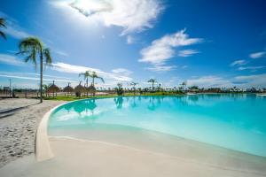 a large swimming pool on a beach with palm trees at Luxury Penthouse - Santa Rosalia Lake and Life Resort in Torre-Pacheco