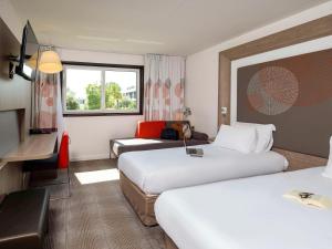 um quarto de hotel com duas camas e uma televisão em Novotel Nantes Carquefou em Carquefou