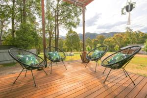 three chairs sitting on a wooden deck with a view at Ville Views in Harrietville