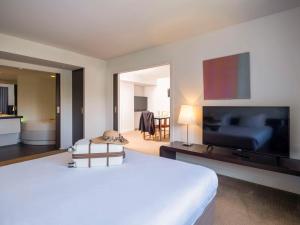 ein Hotelzimmer mit einem Bett und einem Flachbild-TV in der Unterkunft Novotel Nantes Centre Gare in Nantes