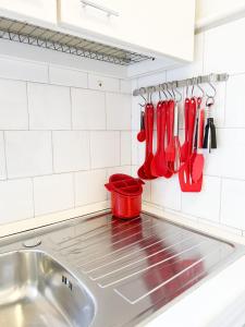 um lavatório de cozinha com utensílios vermelhos na parede em Como view apartment em Como