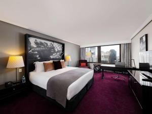 a bedroom with a large bed and a desk and a piano at Sofitel Brisbane Central in Brisbane