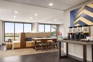 a restaurant with a bar and a counter with chairs at Hampton Inn Kansas City - Airport in Kansas City