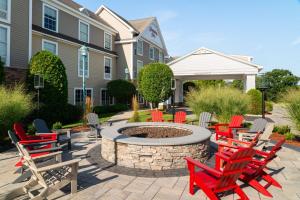 d'une terrasse avec des chaises rouges et un foyer extérieur. dans l'établissement Hampton Inn South Kingstown - Newport Area, à South Kingstown