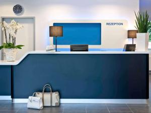 a reception desk in an office with a blue wall at Ibis budget Koeln Messe in Cologne