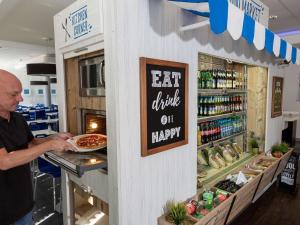 a man getting a pizza from a counter in a store at Ibis budget Koeln Messe in Cologne