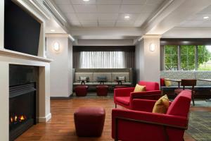 a waiting room with red chairs and a fireplace at Hampton Inn South Kingstown - Newport Area in South Kingstown
