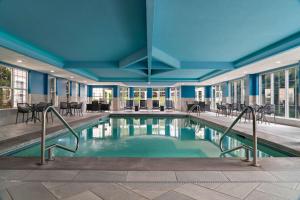 uma piscina num hotel com cadeiras e mesas em Hampton Inn South Kingstown - Newport Area em South Kingstown