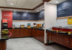 a kitchen with wooden cabinets and a counter with food at Hampton Inn South Kingstown - Newport Area in South Kingstown