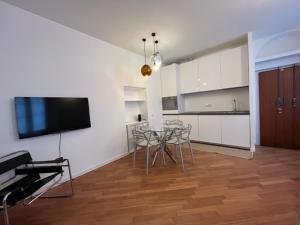 a kitchen with a table and chairs and a tv on a wall at Casa Pagano Un pezzo di cielo su Milano in Milan