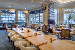 a restaurant with wooden tables and chairs and windows at Hilton Garden Inn St. Louis/O'Fallon in O'Fallon