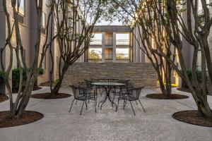 a table and chairs in a courtyard with trees at La Quinta by Wyndham Round Rock North in Round Rock