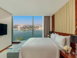 a bedroom with a large bed and a large window at Fairmont Bab Al Bahr in Abu Dhabi