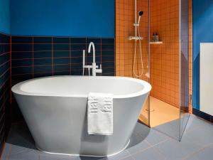 a bath tub in a bathroom with blue and orange tiles at 25hours Hotel Hamburg HafenCity in Hamburg