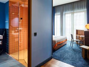 ein Hotelzimmer mit einer Dusche und einem Schlafzimmer in der Unterkunft 25hours Hotel Hamburg HafenCity in Hamburg