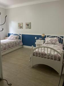 Suite em linda casa em Jurerê internacional في فلوريانوبوليس: سريرين في غرفة نوم بجدران زرقاء وبيضاء