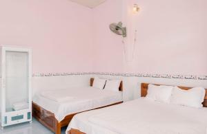 2 camas en una habitación con paredes blancas y espejo en Phương Tú Hostel en Xuyên Mộc