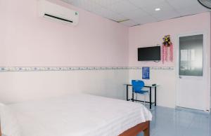 1 dormitorio blanco con 1 cama y 1 silla azul en Phương Tú Hostel en Xuyên Mộc