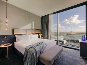 a bedroom with a large bed and a large window at Pullman Auckland Airport in Auckland
