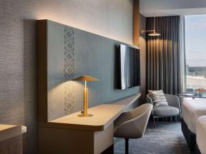 a hotel room with a bed and a desk with a lamp at Pullman Auckland Airport in Auckland