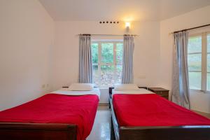 two beds in a room with a window at Nature Routes Cottage in Munnar