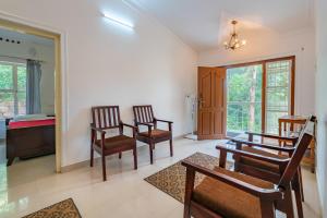 sala de estar con 2 sillas y mesa en Nature Routes Cottage en Munnar