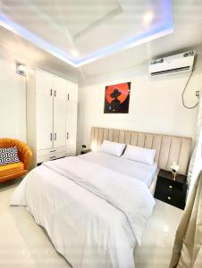 a bedroom with a large white bed and a room with at Blueprint Apartment in Akure