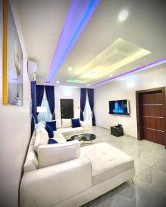 a living room with a white couch and a tv at Blueprint Apartment in Akure