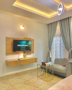 ein Wohnzimmer mit einem Sofa und einem TV in der Unterkunft Blueprint Apartment in Akure