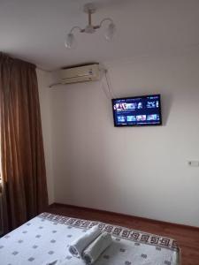 1 dormitorio con 1 cama y TV en la pared en Трешка на Автовокзале, en Kyzylorda