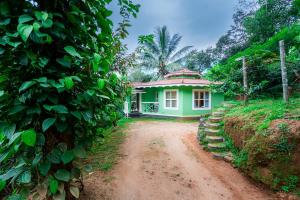 una piccola casa verde su una strada sterrata di Nature Routes Cottage a Munnar