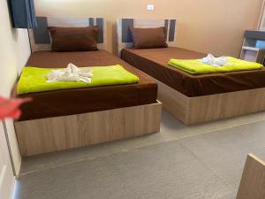 Dos camas en una habitación con toallas amarillas. en ทับศิลารีสอร์ท Tubsila Resort en Chongsadao
