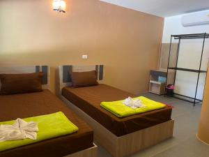 duas camas num quarto com lençóis amarelos em ทับศิลารีสอร์ท Tubsila Resort em Chongsadao