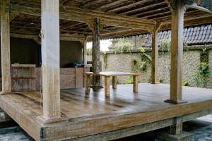 a wooden porch with a table on a wooden deck at Alvia Joglo House & Private Pool in Tampaksiring