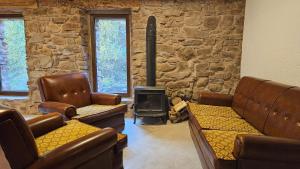 ein Wohnzimmer mit Ledersesseln und einem Holzofen in der Unterkunft El Najerilla. Casa de pueblo in Villavelayo + 12 Fotos