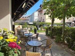 eine Außenterrasse mit Tischen, Stühlen und Blumen in der Unterkunft Le Divona in Divonne-les-Bains