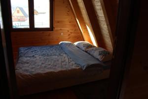 a bed in a wooden room with two windows at Three Houses in Žabljak