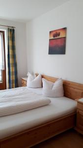 Una cama con sábanas blancas y almohadas. en Brunnerhof, en Strassen