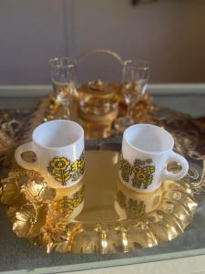 a table with two mugs on a gold tray at WB Lounge - Mohandessin Apartment in Cairo