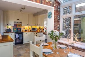 une cuisine avec une table en bois et des chaises ainsi qu'une salle à manger dans l'établissement 4 Malvern House by Big Skies Cottages, à Trimingham