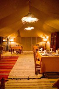 um quarto com mesas e cadeiras numa tenda em Sky View Camp em Merzouga