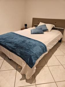een bed met een blauwe deken erop bij Le Contemporain, au pied de la chaîne du JURA, 3 chambres in Thoiry