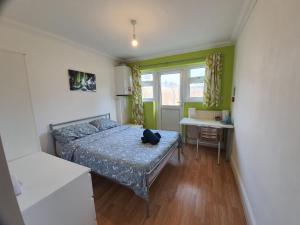 - une chambre avec un lit et un bureau dans l'établissement Eastwood Rooms, à Goodmayes