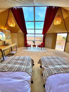 two beds in a room with a view of the desert at Sky View Camp in Merzouga