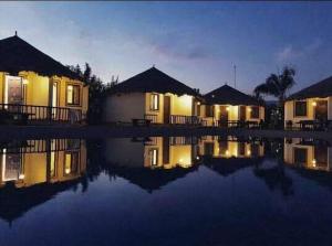 a group of houses at night next to a body of water at The Village Resort in Kodāe