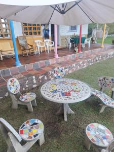 eine Terrasse mit einem Tisch, Stühlen und einem Sonnenschirm in der Unterkunft Finca Campestre Villa Gladys in Guatapé