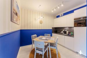 uma cozinha com paredes azuis e uma mesa e cadeiras em 3L Apartments Nadmorskie Tarasy em Kolobrzeg