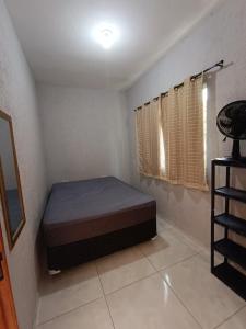 a small bedroom with a bed and a window at Casa de Praia in Ubatuba