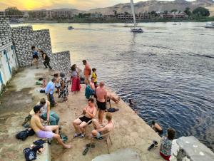 um grupo de pessoas sentadas na praia perto da água em Go Inn Backpackers em Aswan